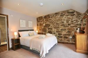 a bedroom with a bed with a stone wall at Beach View in Benllech