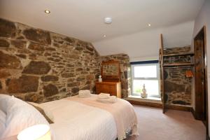 a bedroom with a stone wall with a bed at Beach View in Benllech