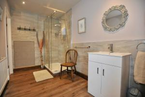 a bathroom with a shower and a sink and a chair at Beach View in Benllech +13 photos
