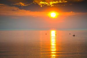 a person in a boat in the ocean at sunset at Beach View in Benllech