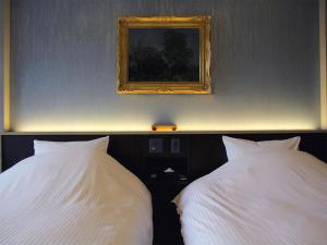2 weiße Betten in einem Schlafzimmer mit einem Bild an der Wand in der Unterkunft Mizno Hotel in Fujikawaguchiko
