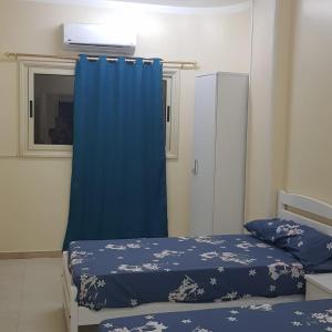 a bedroom with two beds and a blue curtain at Sweet Home 5- No Egyptian in Hurghada