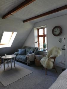 uma sala de estar com um sofá e um relógio na parede em Tankefuld Living's Horsefarm em Svendborg