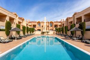 a resort pool with chairs and umbrellas at Baia da Luz - Poolview Loft Aparment in Luz
