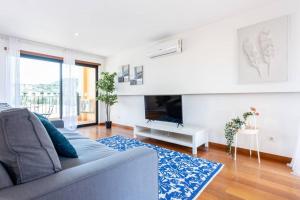 a living room with a couch and a tv at Baia da Luz - Poolview Loft Aparment in Luz