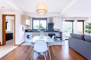 a kitchen and living room with a table and a couch at Baia da Luz - Poolview Loft Aparment in Luz