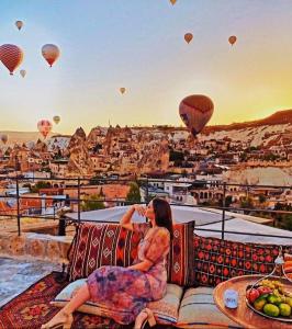 a woman sitting on a couch watching hot air balloons at Tekkaya Cave Hotel in Goreme
