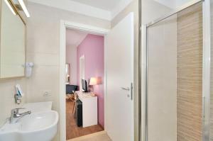 a bathroom with a sink and a glass shower door at Hotel Nederland in Caorle +82 photos