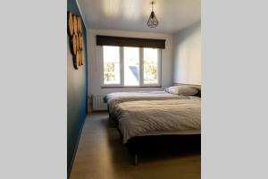 1 dormitorio con 2 camas y ventana en Au Comilfo en Malmedy
