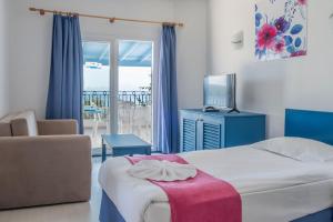 1 dormitorio con cama, TV y balcón en Bodrum Holiday Resort & Spa, en Bodrum City