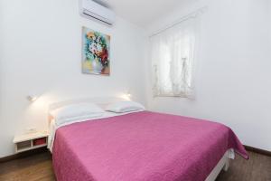 ein weißes Schlafzimmer mit einem lila Bett und einem Fenster in der Unterkunft Kastela Agneza Apartment (2+1) near SplitAirport in Kaštela
