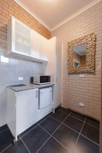 a kitchen with white cabinets and a microwave at Colac Mid City Motor Inn in Colac