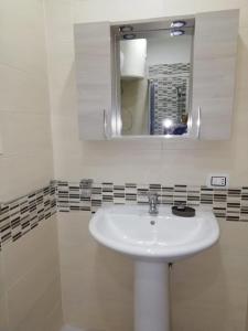 La salle de bains est pourvue d'un lavabo blanc et d'un miroir. dans l'établissement otto di denari, à Naples