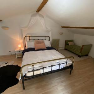a bedroom with a bed and a green chair at La Fermette Aux Canards in Savigny-Lévescault