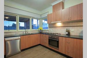 una cocina con armarios de madera y electrodomésticos de acero inoxidable en Victoria House- Great location, en Corowa