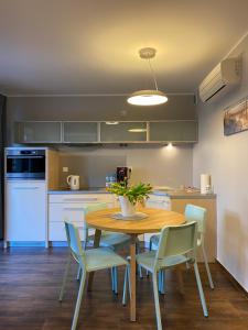 a kitchen with a wooden table and chairs and a kitchen with white appliances at Apartament BalticPark Stegna in Stegna