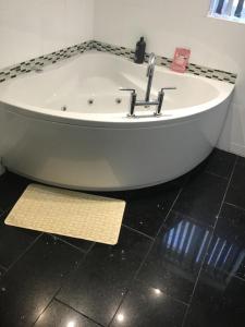 a bath tub in a bathroom with a yellow rug at B&B Dorwyn Manor in Avebury