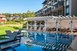 a swimming pool with chairs and a building at Grandoise 2 Bed Zimbali Suites in Ballito