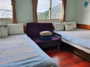 um quarto com duas camas e uma cadeira e uma janela em Ching Yue B&B em Jiufen