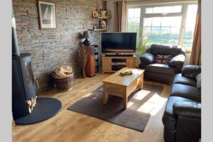a living room with a couch and a television at ** Beautiful Scenery - Cyclists & Walkers Dream ** Log Burner ** Peaceful Hamlet ** in Redruth