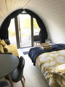 Lough Erne Glamping Pod في إنيسكيلين: غرفة نوم بسرير وطاولة وكراسي