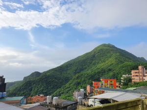 a mountain covered in green trees next to a city at Ching Yue B&B in Jiufen