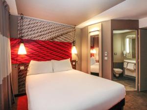 a bedroom with a large white bed with a red headboard at ibis Cahors in Cahors