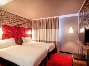 a hotel room with two beds and a television at ibis Cahors in Cahors