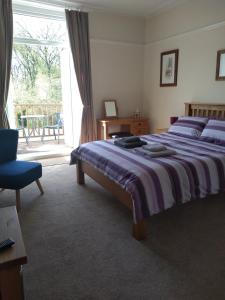 - une chambre avec un grand lit et une porte coulissante en verre dans l'établissement Tirionfa Guest House, à Criccieth