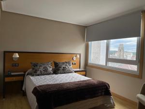 a bedroom with a bed and a large window at Aparthotel Arenteiro in Carballino