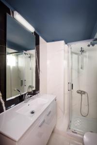 a white bathroom with a sink and a shower at Hotel Segas in Loutraki