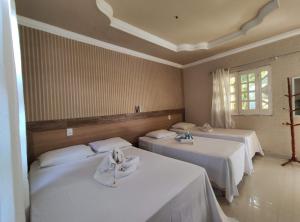 a room with two beds with white sheets at Pousada Porto dos Corais in Maragogi