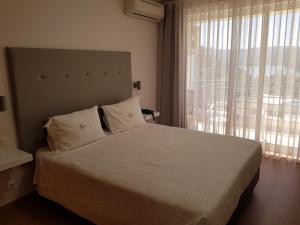 a bedroom with a bed and a large window at Hotel Lagoa Azul do Geres in Geres