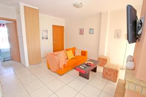 een woonkamer met een oranje bank en een tv bij Apartment near the sea and the Athens airport , Artemida in Artemida