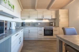 a kitchen with white cabinets and a wooden table at Ferienhaus Norderoog in Dagebüll