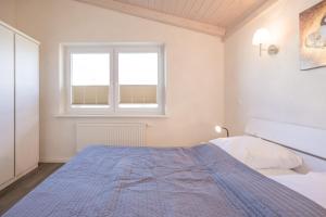 ダゲビュルにあるFerienhaus Föhrのベッドルーム1室(青い毛布付きのベッド1台付)