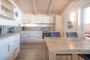 eine Küche mit weißen Schränken und einem Holztisch in der Unterkunft Ferienhaus Stockente in Dagebüll