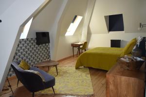 a bedroom with a bed and a couch and a chair at Chambres d'Hôtes Le Clos des Marronniers in Douvres-la-Délivrande