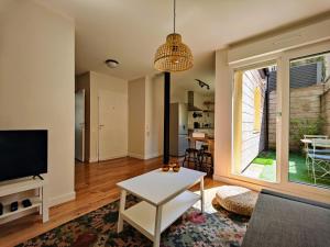 un salon avec une télévision et une table dans l'établissement Le Bienvenu - T2 avec terrasse au coeur de Malo, à Dunkerque