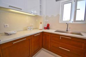 a kitchen with wooden cabinets and a sink and a window at Potamos Deluxe White Apartment in Potamós +11 photos