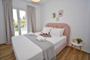 a bedroom with a large white bed with towels on it at Potamos Deluxe White Apartment in Potamós