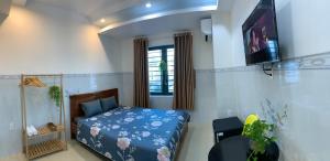 a bedroom with a bed and a tv on a wall at Homestay The Fiii Come&Stay in Vung Tau