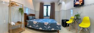 a bedroom with a bed and a table and yellow chairs at The Fiii Homestay&Beauty in Vung Tau
