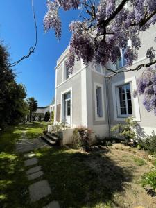 una casa blanca con un árbol floreciente delante de ella en Maison Latour en Cholet