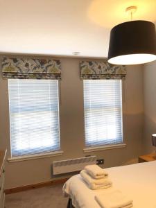 a bedroom with two windows and a bed with towels at The Town House in Dornoch