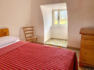 a bedroom with a bed and a chair and a window at Waterfront Villa in Pantelleria