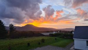 a sunset over a field with a mountain in the background at Braeside Bothy in Dunvegan