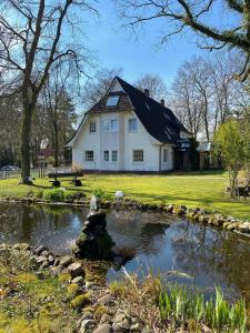 ein Haus mit einem Teich davor in der Unterkunft Landhaus Fillerberg in Wildeshausen