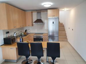 a kitchen with a stainless steel refrigerator and black chairs at Él Rome Duplex in Agaete