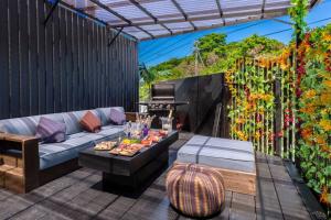een patio met een bank, een tafel en een grill bij Vacation Rental Motobu Grande BBQ機材完備の新築ヴィラ！！ in Motobu